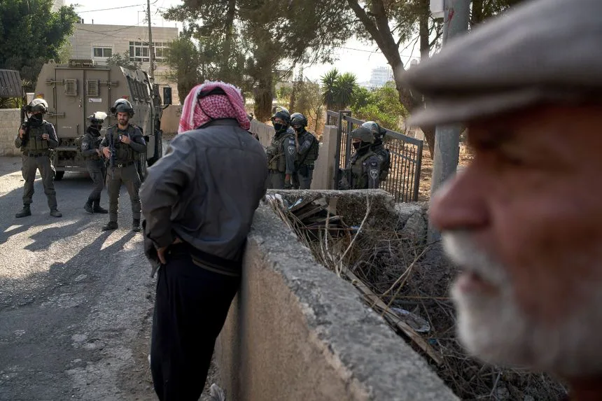Members of Israeli forces block a road, preventing Palestinians from harvesting olives in the West Bank village of Deir Jarir on Wednesday.