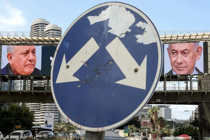 A road sign stands in front of a large billboard featuring Prime Minister Benjamin Netanyahu, right, and Gadi Eisenkot, in Ramat Gan on Tuesday.